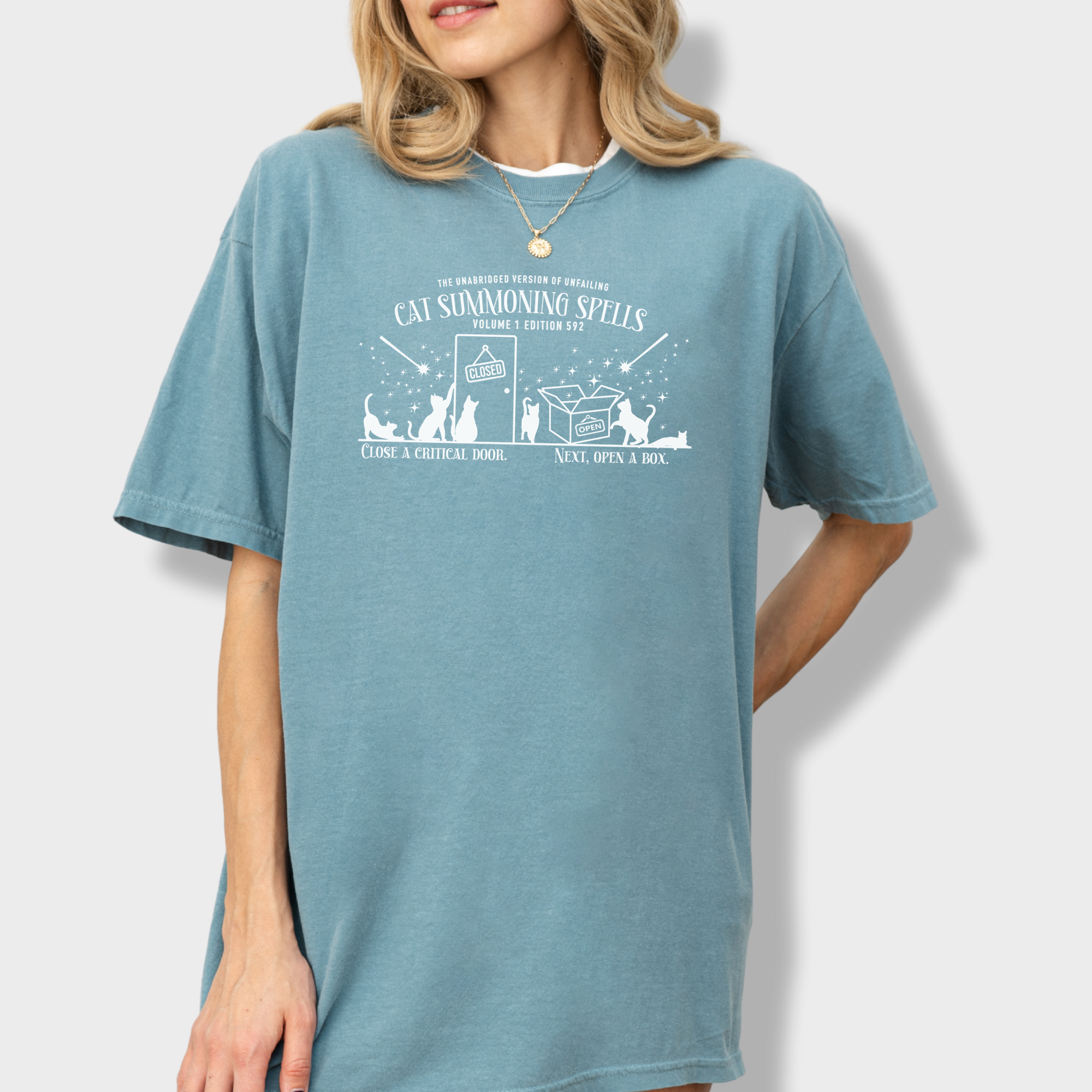 Funny cat magic T-shirt with a simple one-color book design, illustrating spells that summon cats to doors and open boxes.