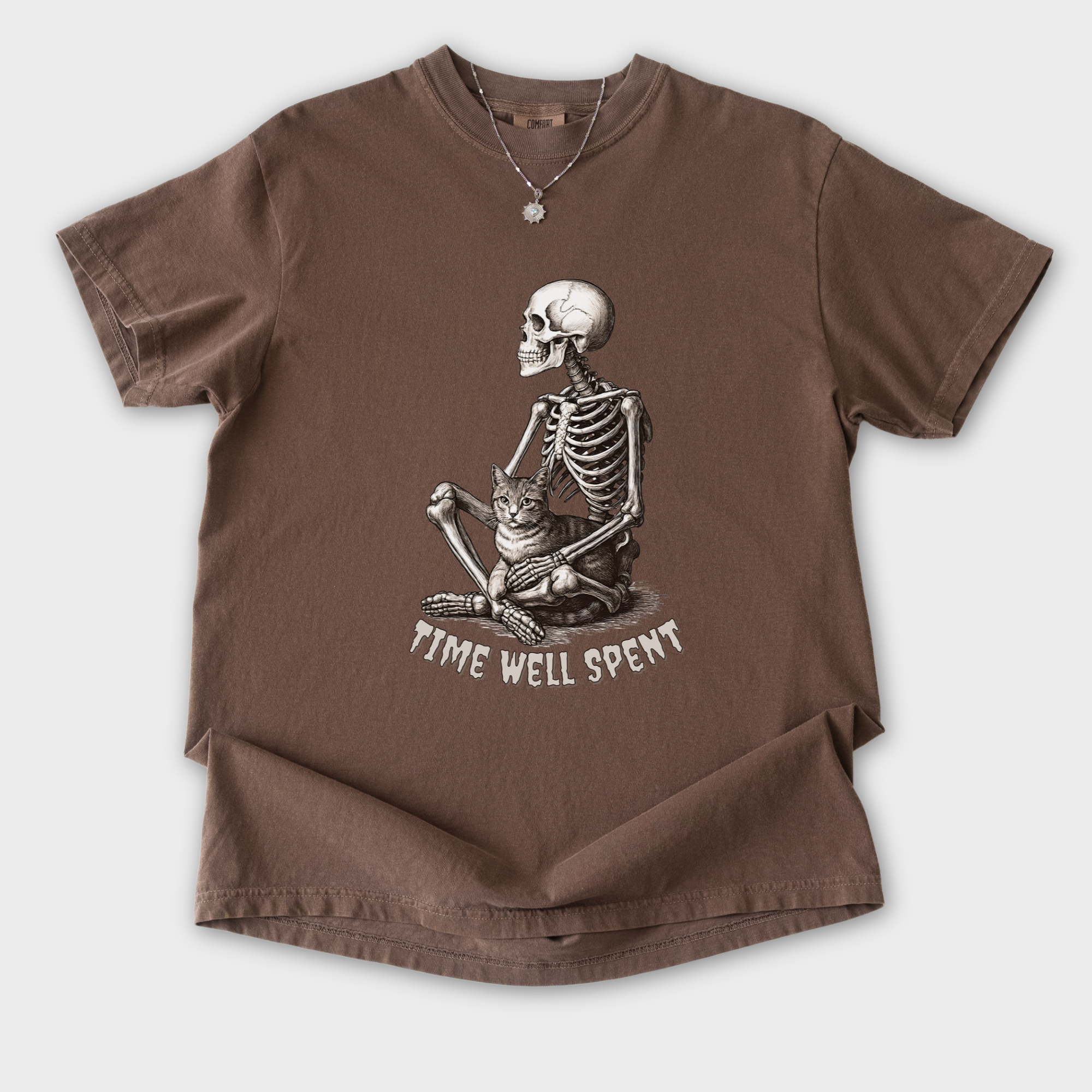 line-art-sit-still-skeleton-petting-cat-cat-skeleton-comfort-colors-t-shirt-in-espresso - Espresso Flat Lay Front