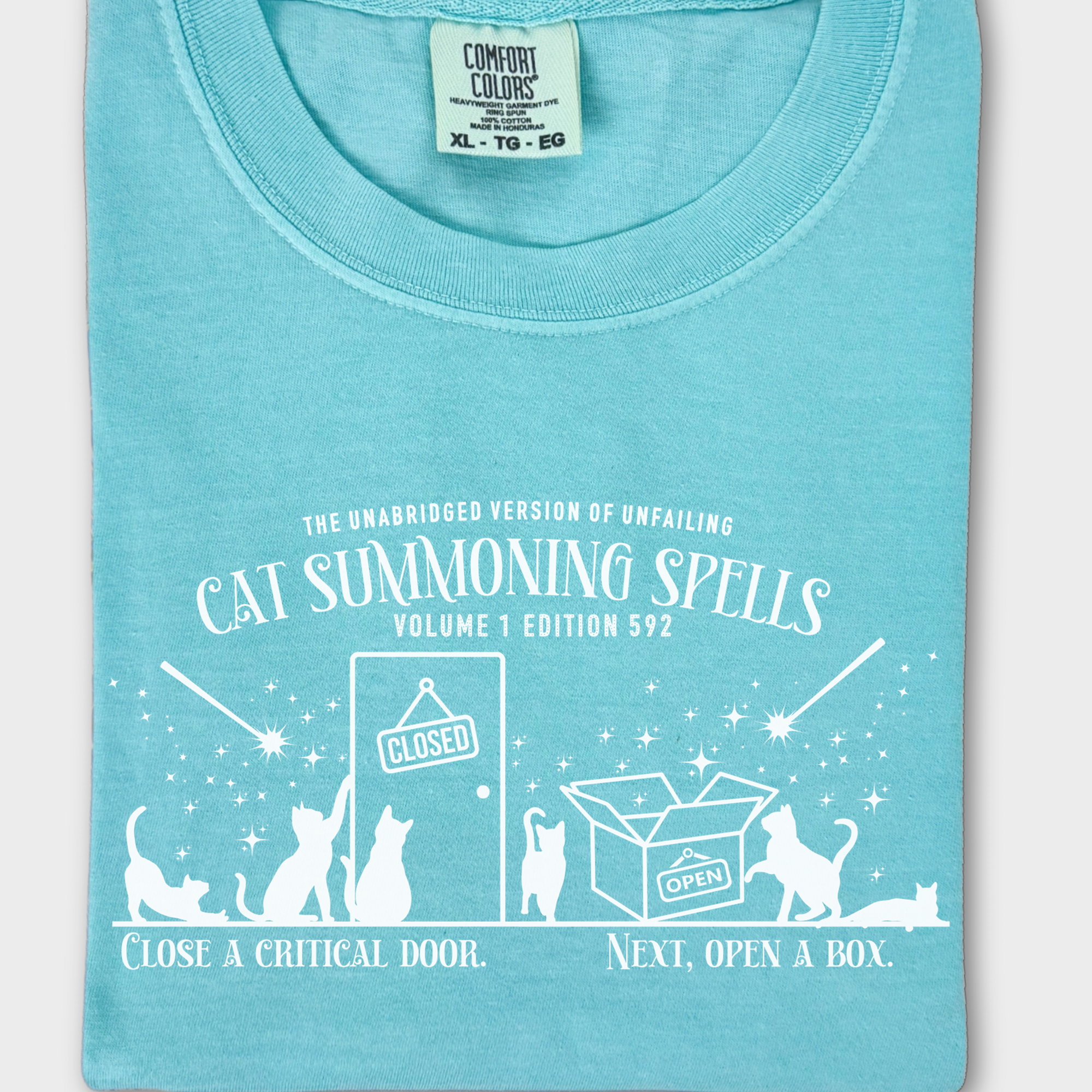 Unique retro-style cat T-shirt with a mystical spellbook graphic, humorously showing how cats magically appear at doors and boxes.