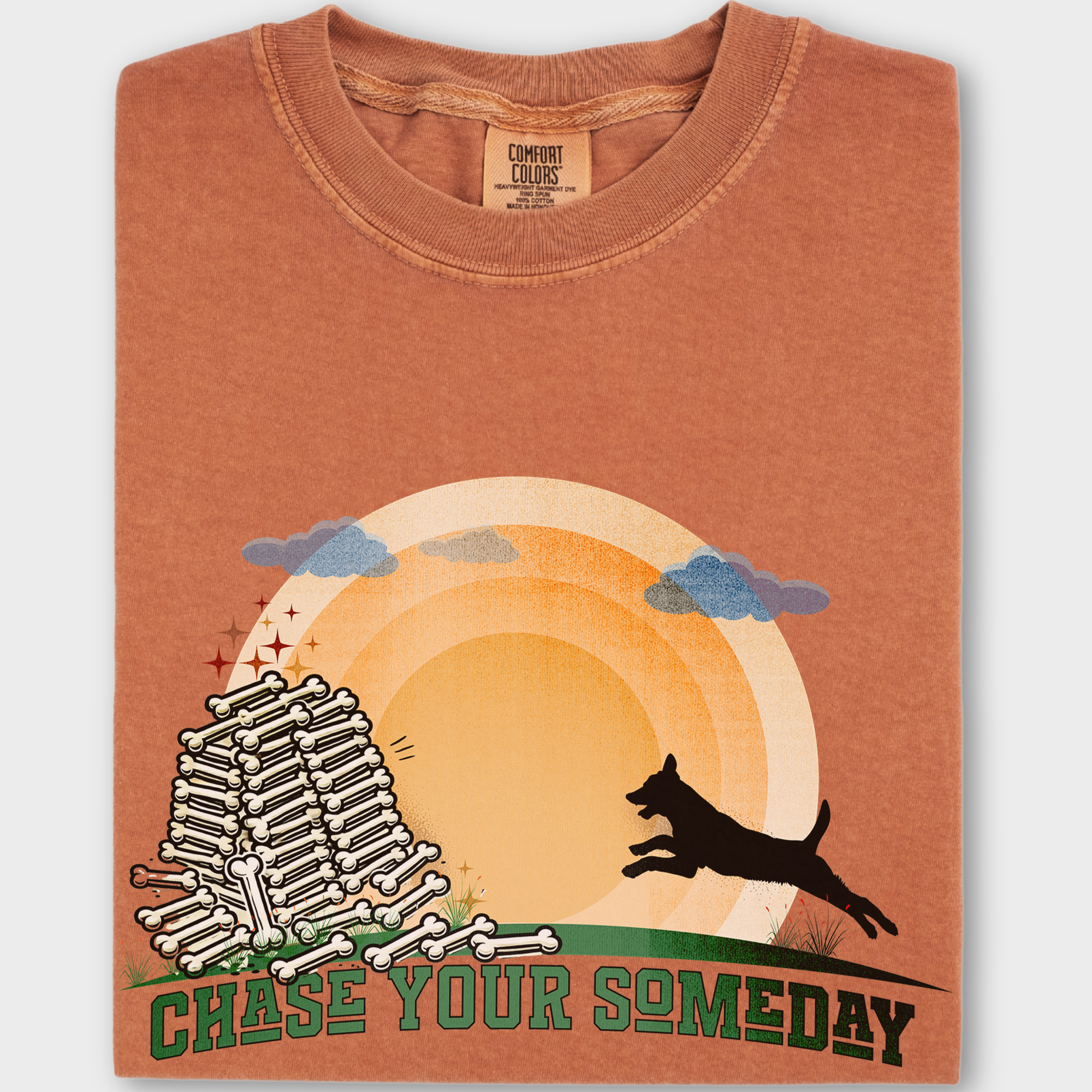 Inspirational dog T-shirt featuring a running pup chasing the sun toward a pile of bones with 'Chase Your Someday' text