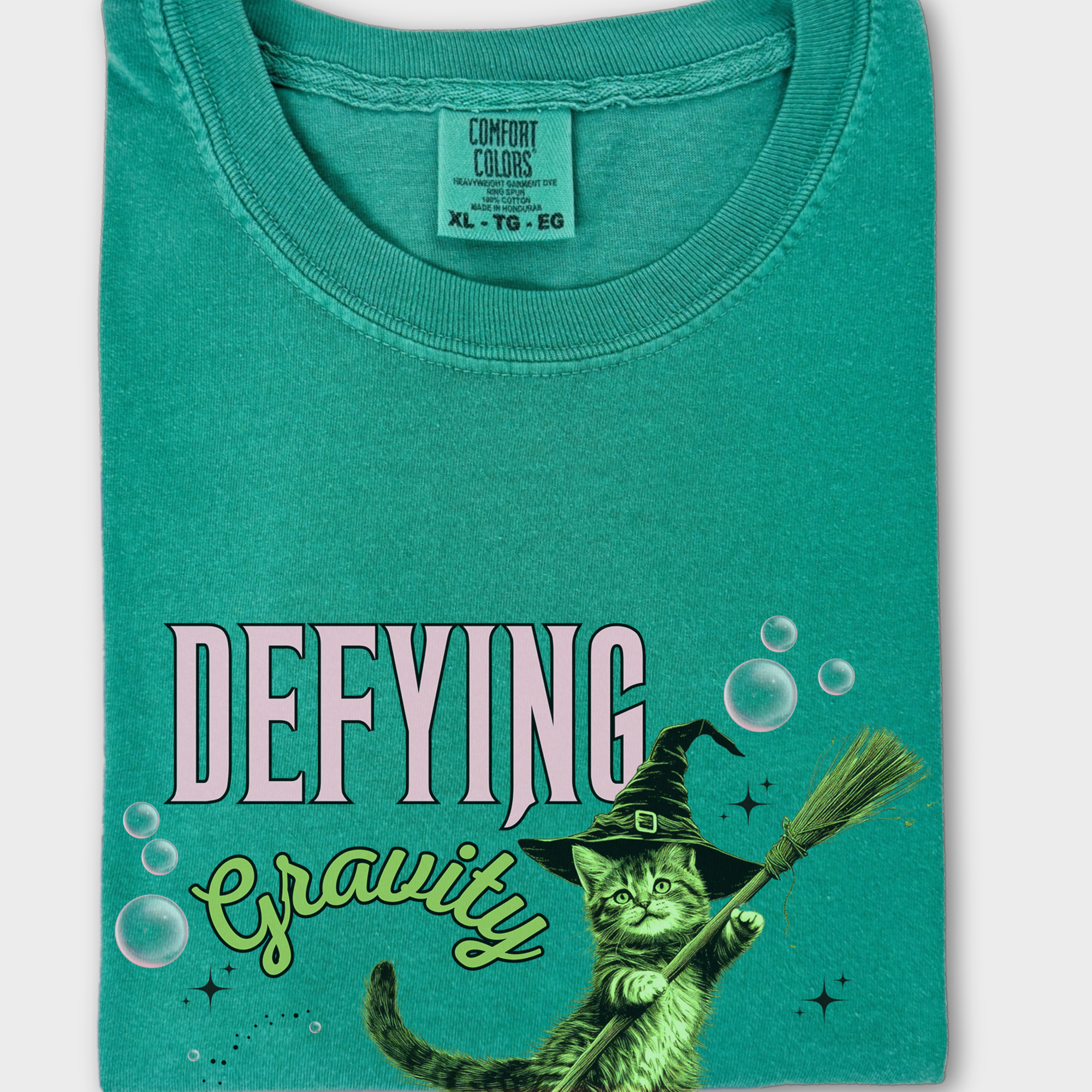 Whimsical cat-themed T-shirt featuring a green levitating witch cat in vintage style. Comfortable and stylish for everyday wear