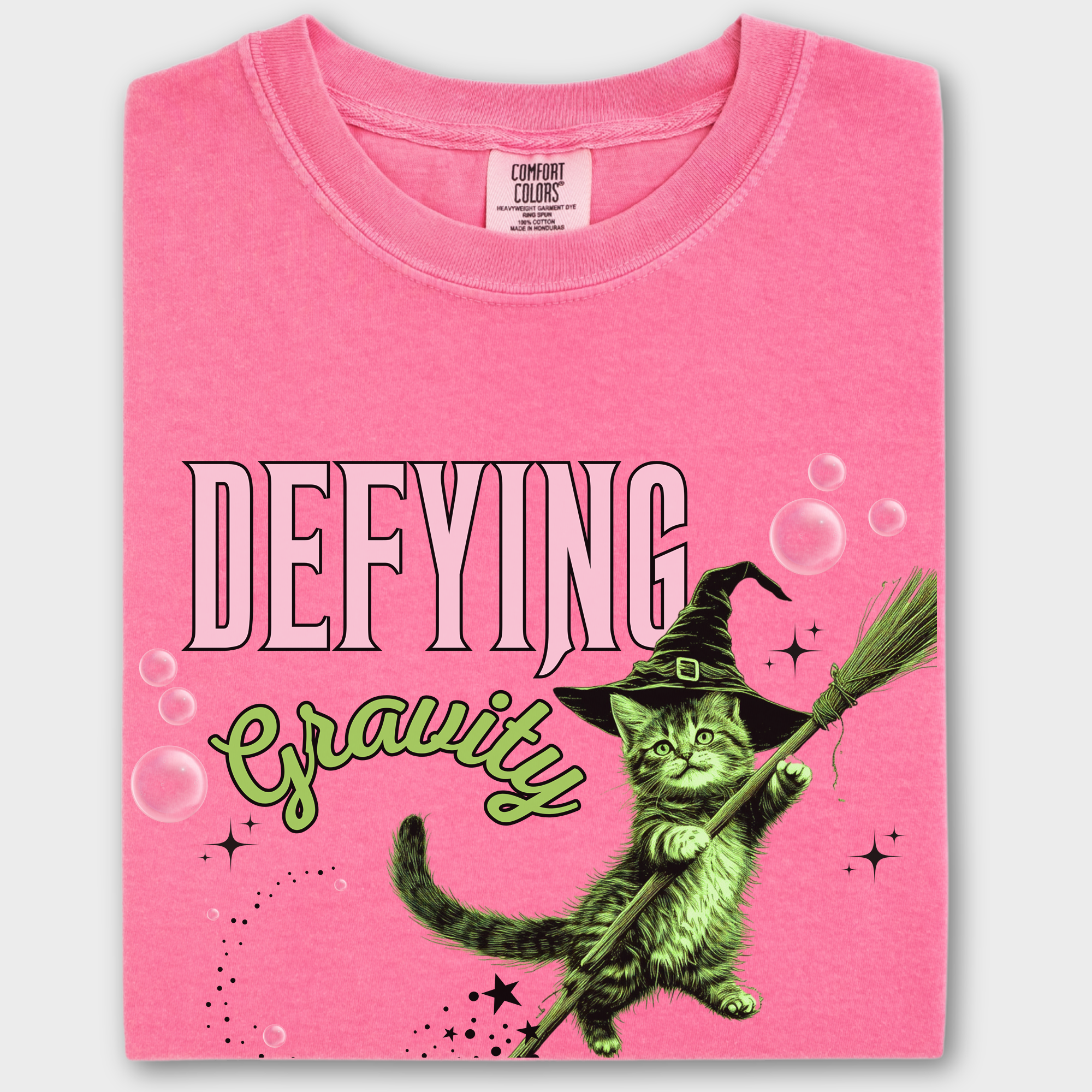 Whimsical cat-themed T-shirt featuring a green levitating witch cat in vintage style. Comfortable and stylish for everyday wear