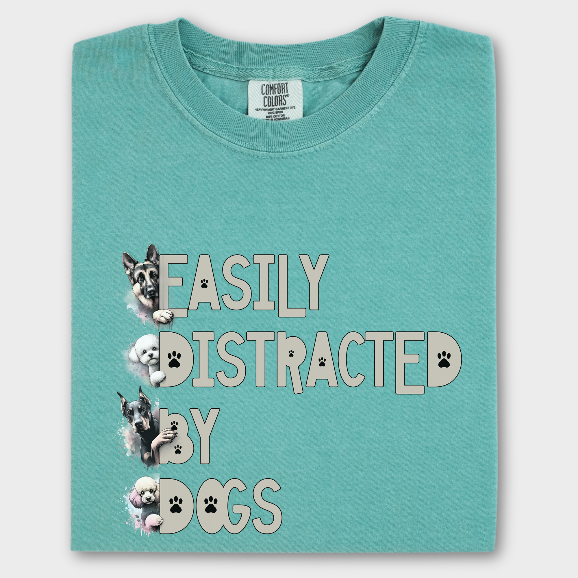 Colorful watercolor dog T-shirt featuring the phrase 'Easily Distracted by Dogs' with illustrations of a German Shepherd, Bichon Frise, Doberman, and Miniature Poodle.