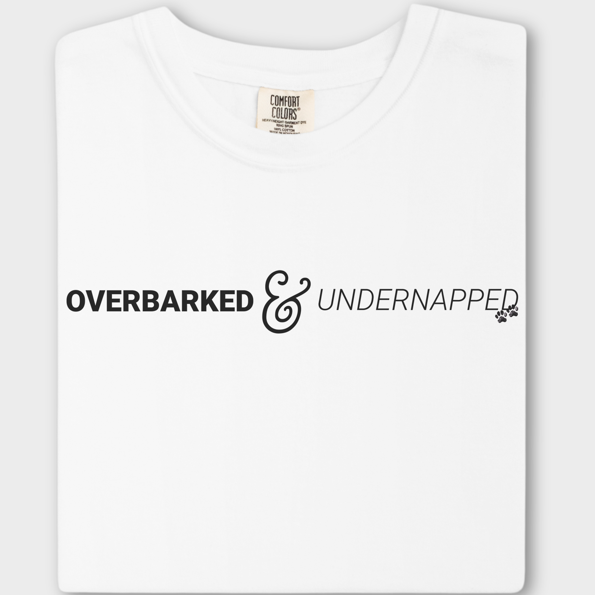 Funny dog lover’s T-shirt featuring the phrase 'Overbarked & Undernapped' with two paw prints, printed on soft cotton.