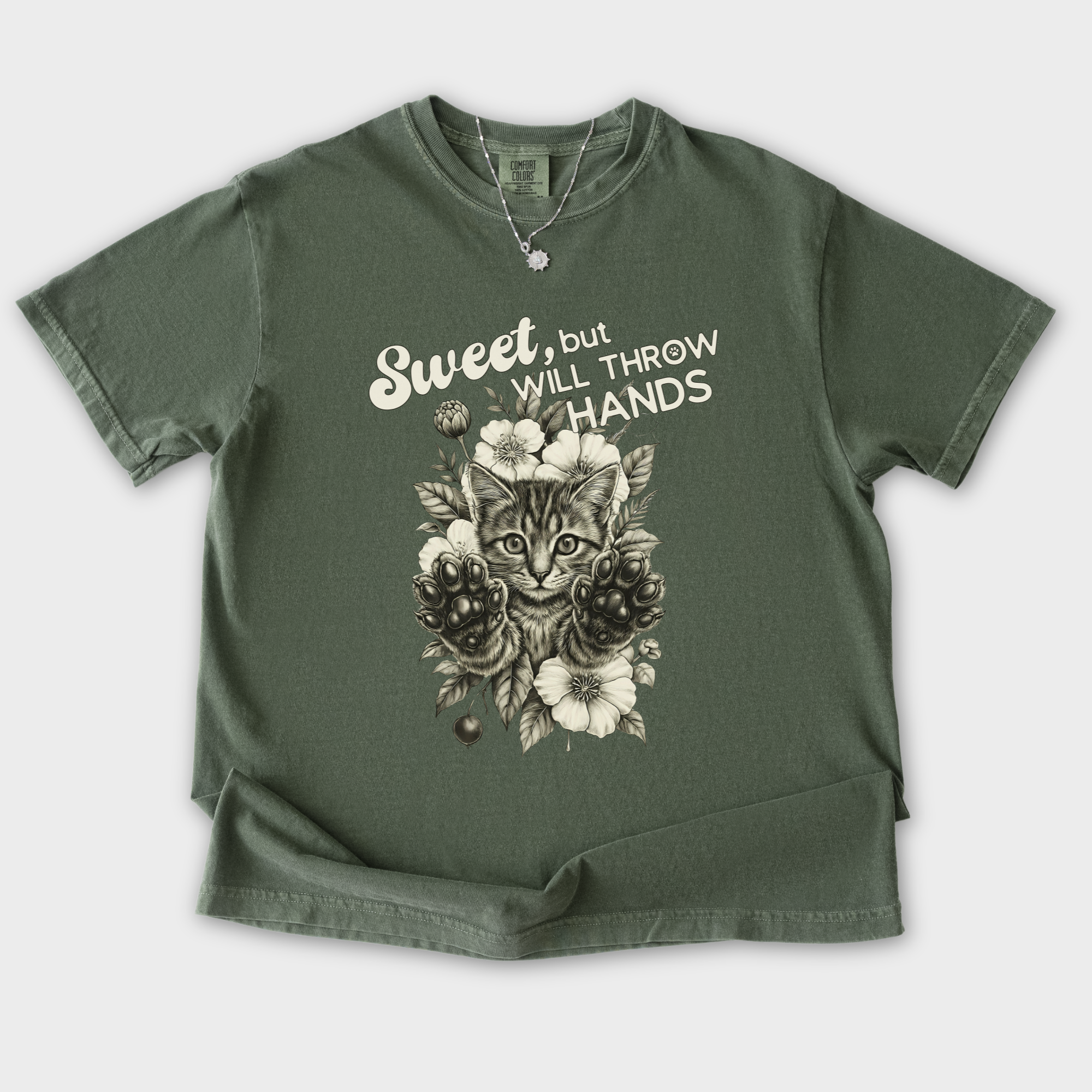 minimalist-sweet-but-will-throw-hands-cat-text-comfort-colors-t-shirt-in-moss - Moss Flat Lay Front