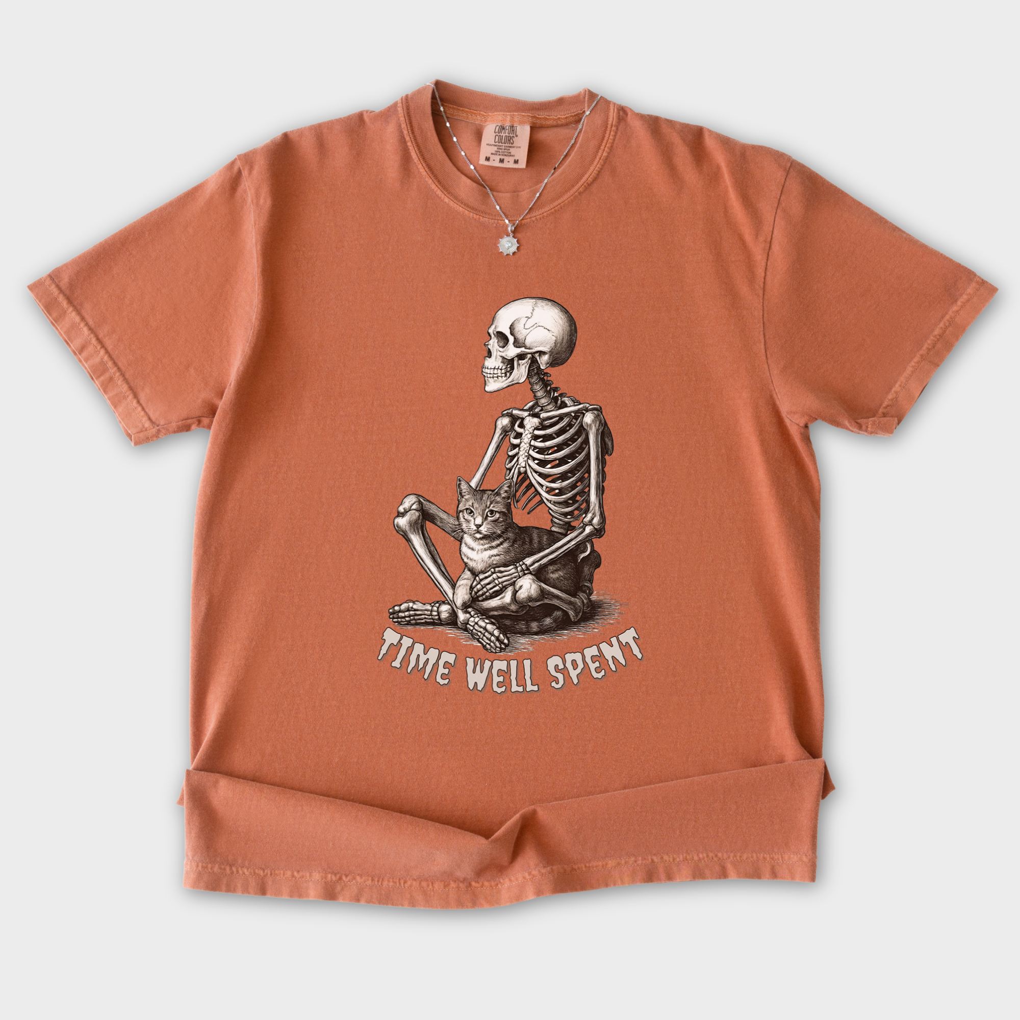 line-art-sit-still-skeleton-petting-cat-cat-skeleton-comfort-colors-t-shirt-in-yam - Yam Flat Lay Front